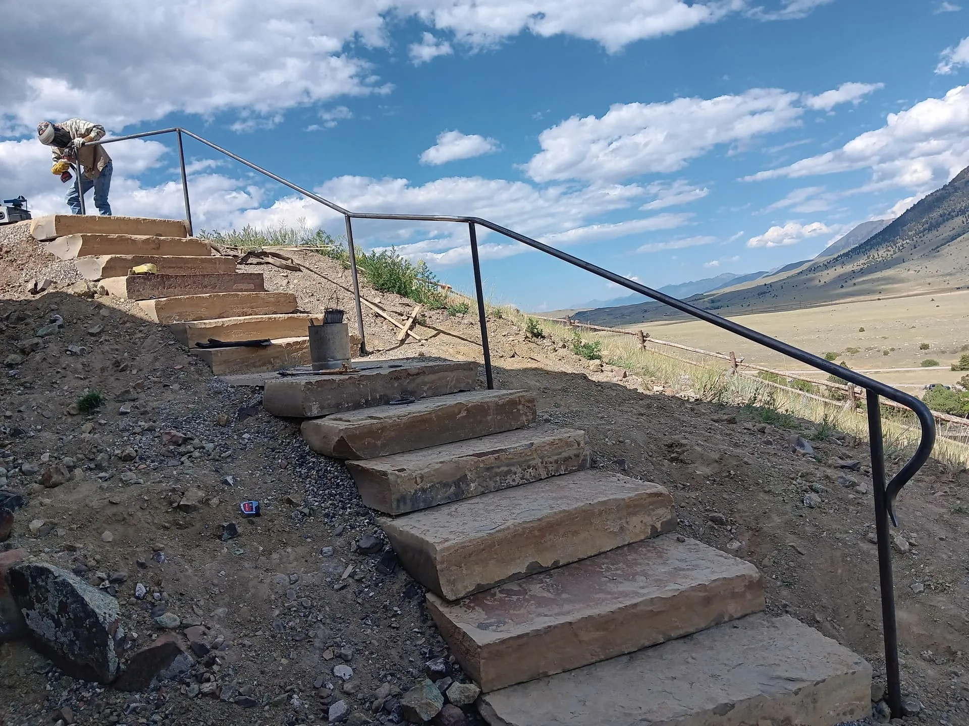Flagstone slab staircase with hand-welded steel railing on a Montana hillside