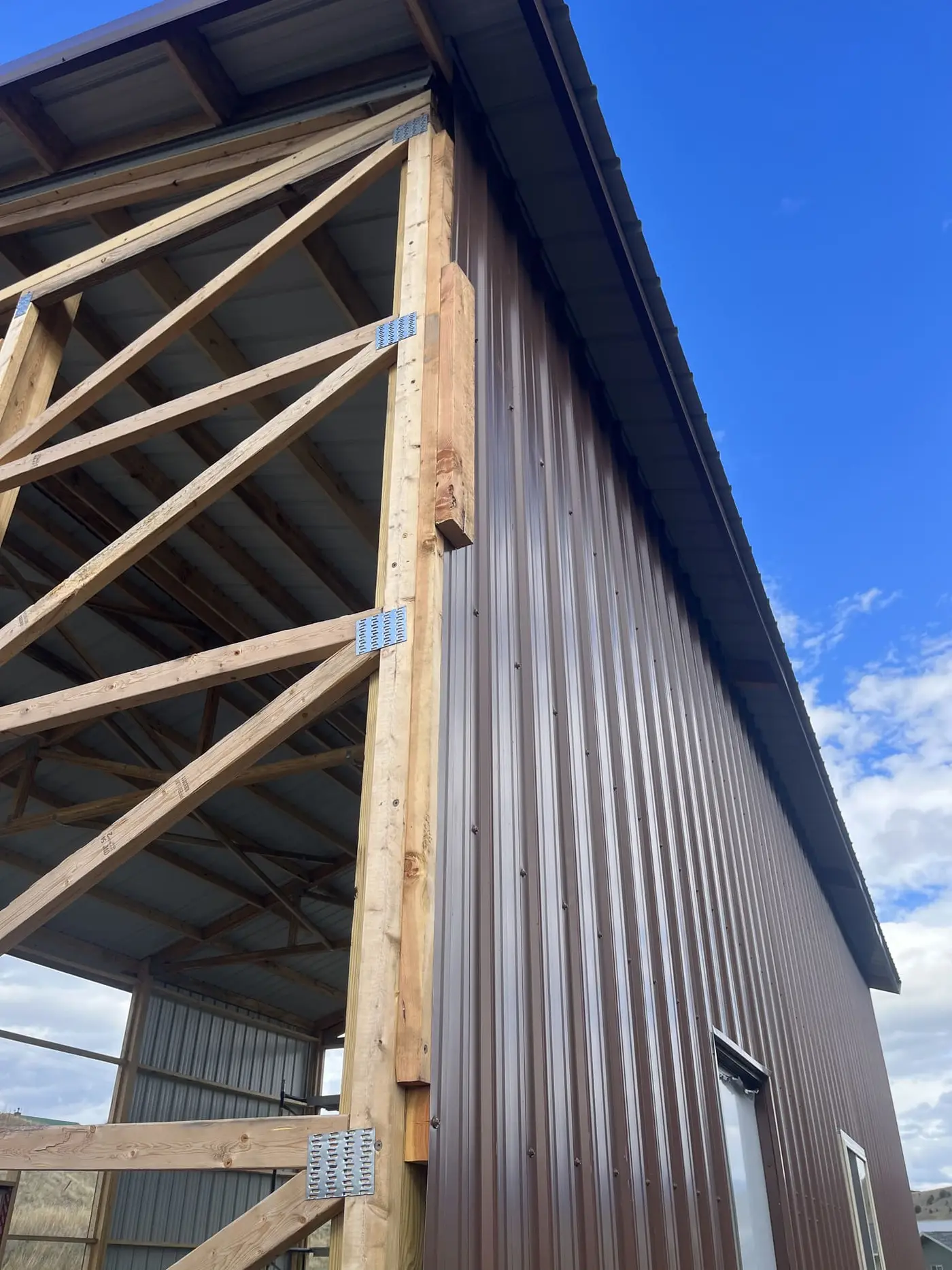 Open-sided pole barn with wood trusses and a metal roof