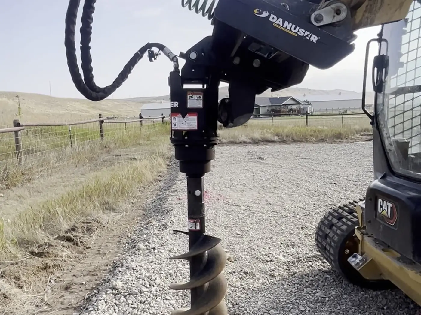 Machine-mounted auger drilling post holes for a pole barn