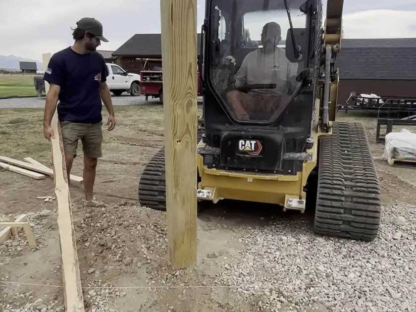 Crew setting a pole barn post with a track loader