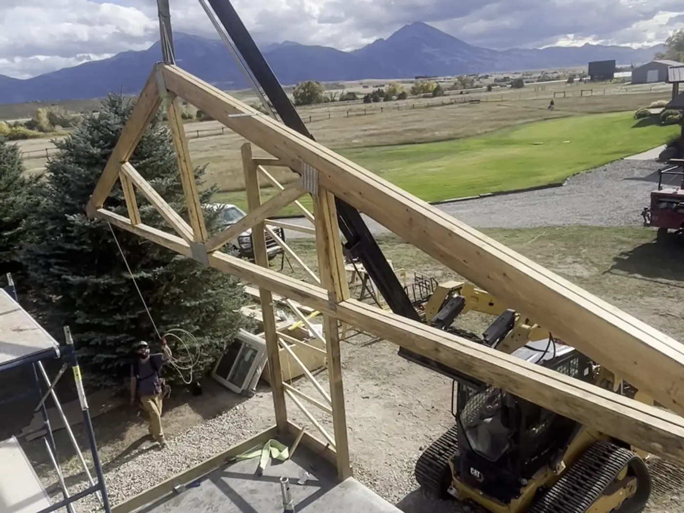 Roof truss being lifted into place by a track loader