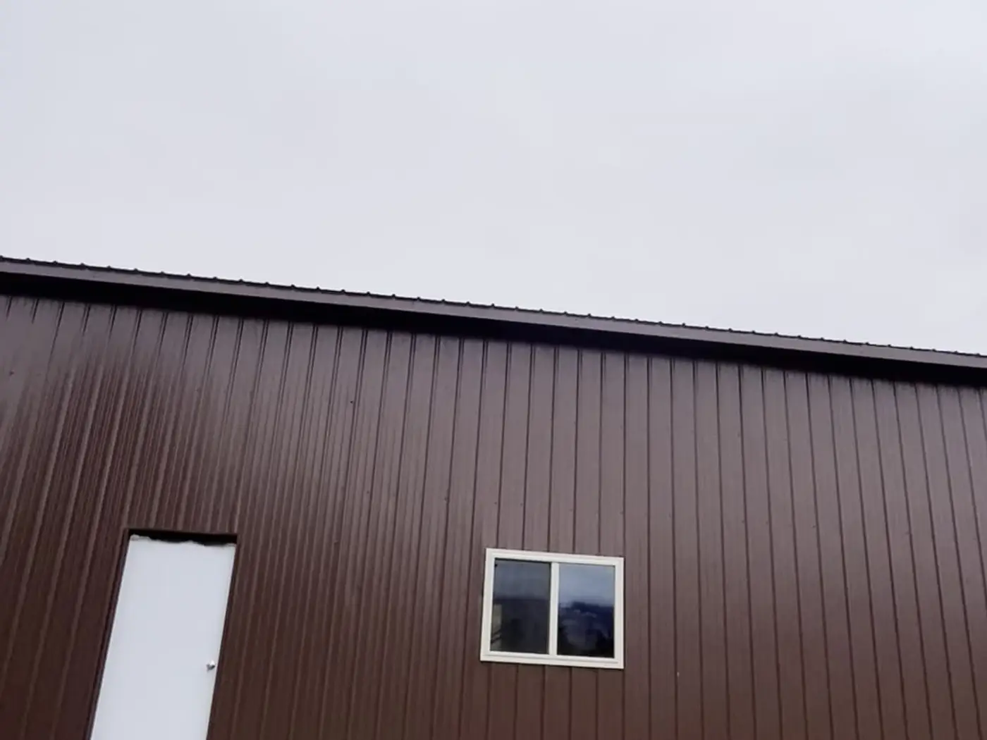 Close-up of the finished pole barn wall with walk door and window